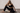 Frau in schwarzem Yoga-Outfit auf dem Boden sitzend