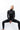 Frau in Yoga-Pose trägt schwarze Jacke und schwarze Leggings